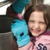 A girl opens a sap bucket at a sugar shack in Kawarthas Northumberland
