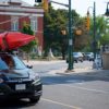 A car with two kayaks on the roof drives through downtown Lakefield