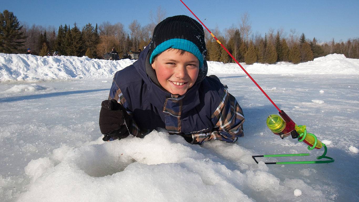 A kid poses near an ice fishing hole