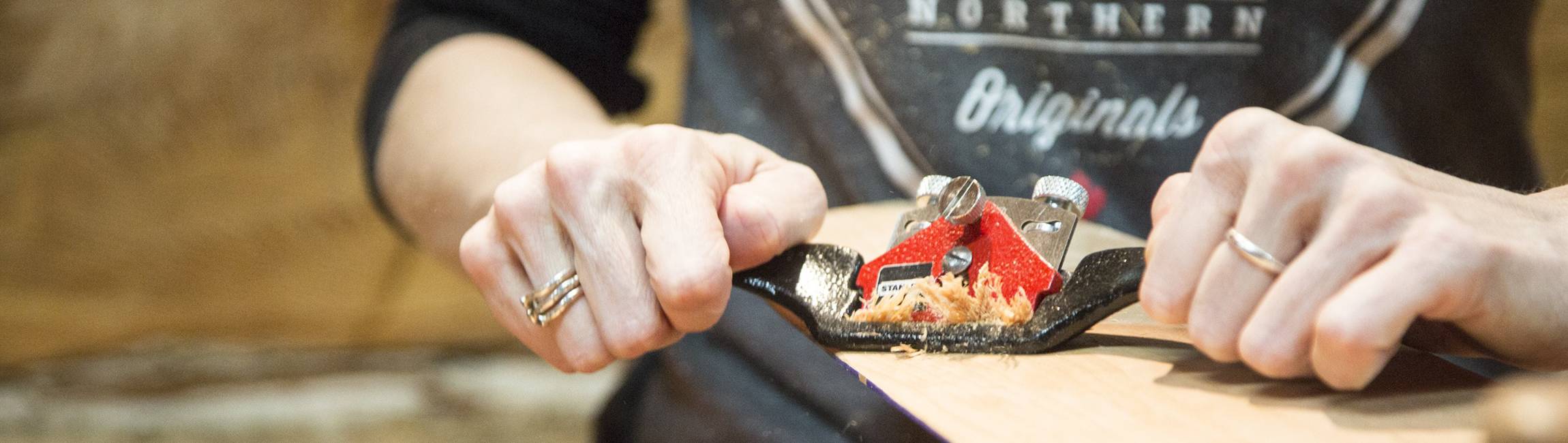 Closeup of hands using a spokeshave to carve a paddle