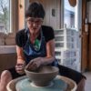 A woman sculpts a bowl on a pottery wheel