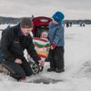 Family beside an ice fishing hold at OFAH Family Day