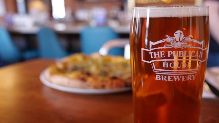 Pint of Publican House Square Nail IPA in the foreground with vegetarian pizza in the background