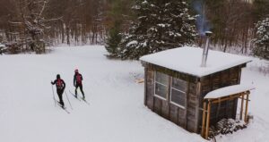 Skiers depart from a snow-covered cabin