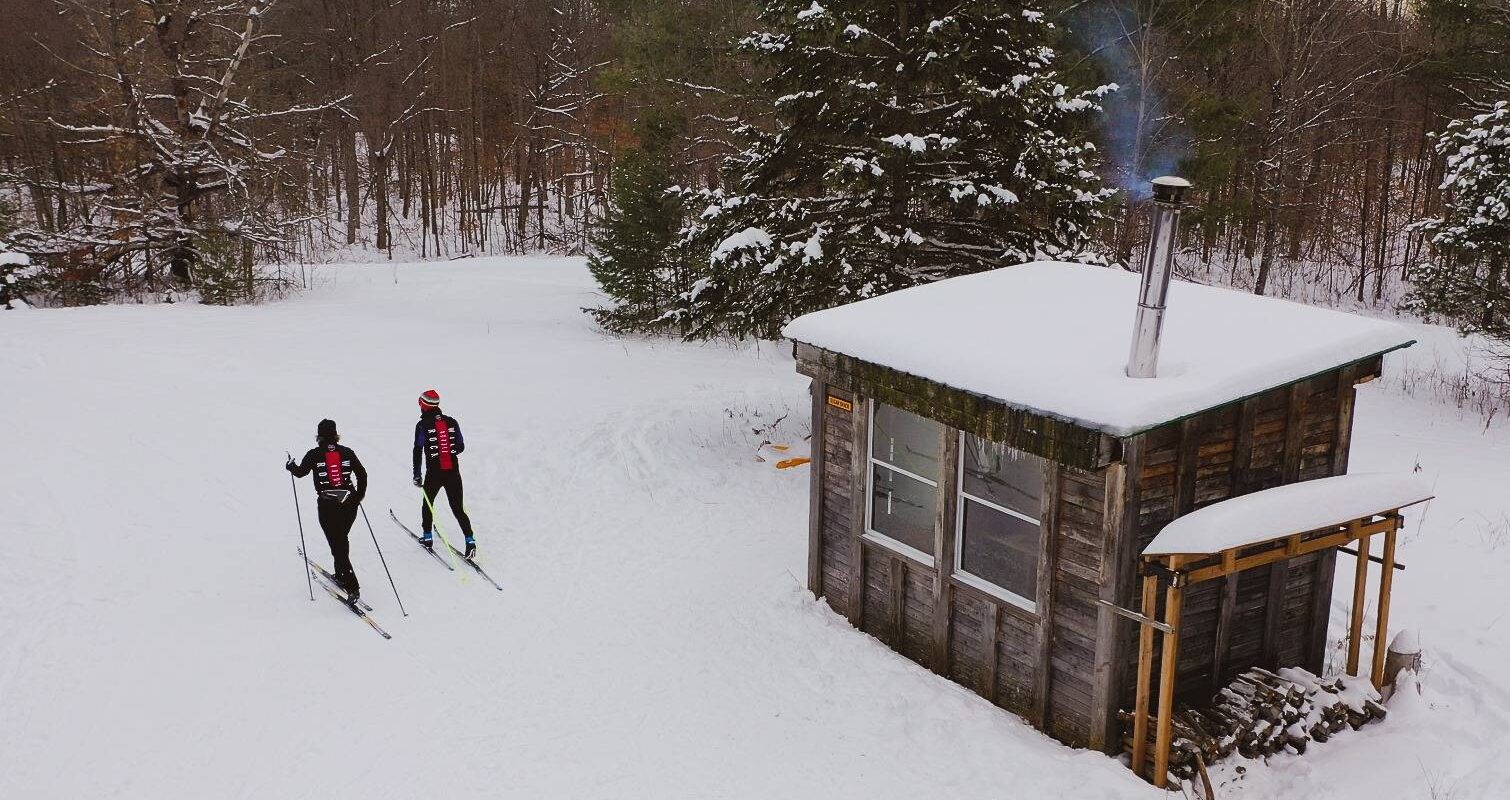 Skiers depart from a snow-covered cabin