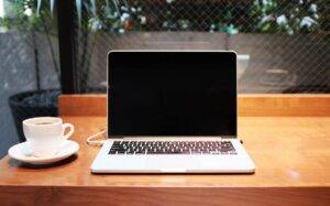 An open laptop with a black screen on a wooden table
