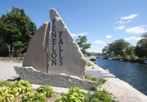 Large stone installation beside the water, reading "Fenelon Falls"