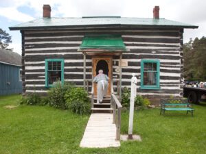 A person climbs the steps of a log cabin