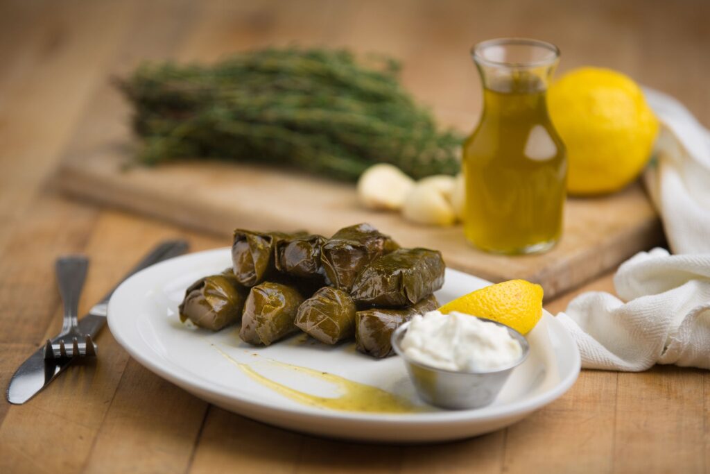 Dolmades on a plate with tzatiki, olive oil, and lemon
