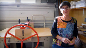 An older woman stnads in the corner of a pottery studio