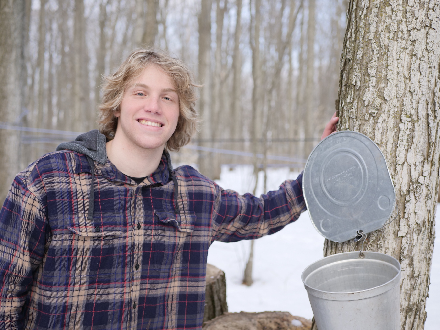 Jeremy Poulin poses beside a tapped maple tree