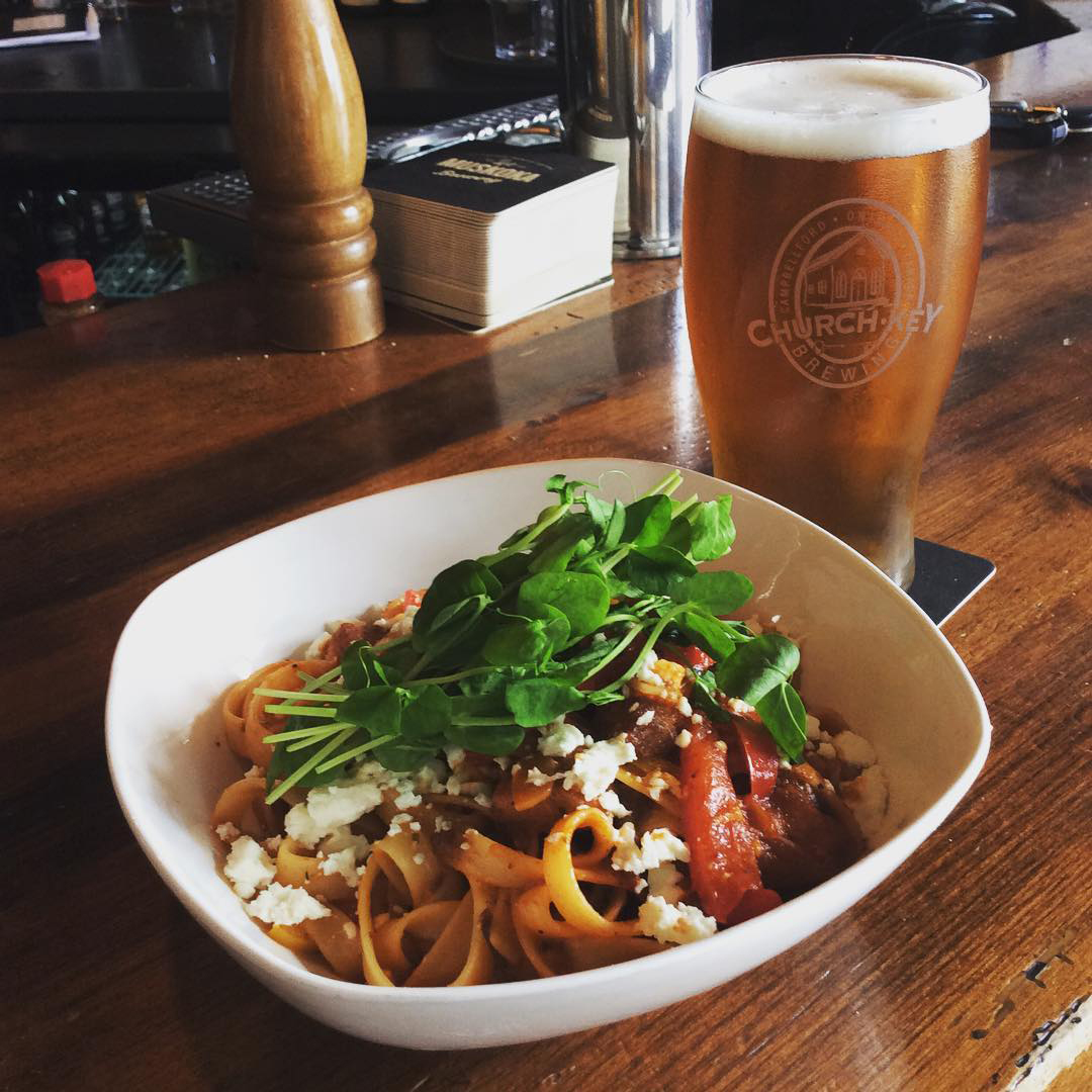 A noodle dish paired with a pint of beer