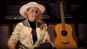 Melissa Payne sits beside her guitar in the seats at Market Hall
