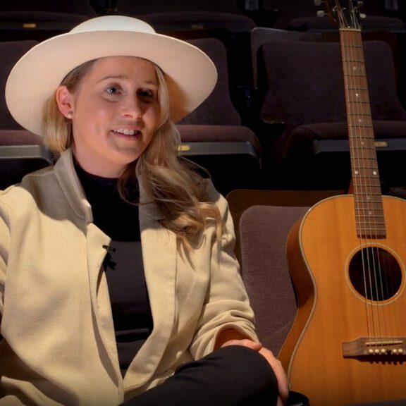 Melissa Payne sits beside her guitar in the seats at Market Hall