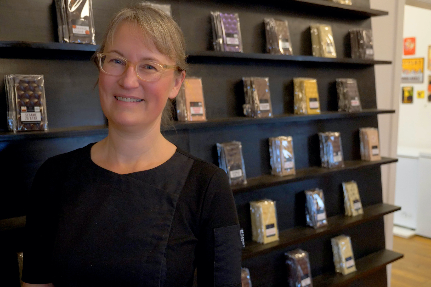 Angela Roest of Centre & Main Chocolate Co. stands in front of a wall of her chocolate bars
