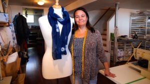 Christine Roberts of Modelia stands beside a tailor's dummy that is wearing a deep blue scarf