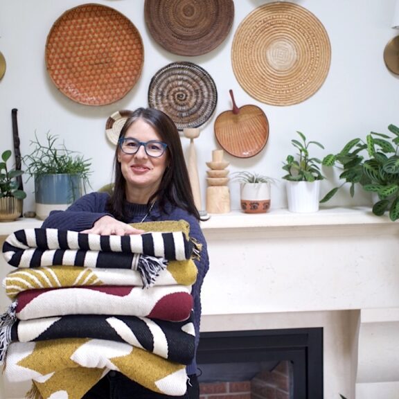 Leslie Robb of Swell Made Co holding a stack of blankets