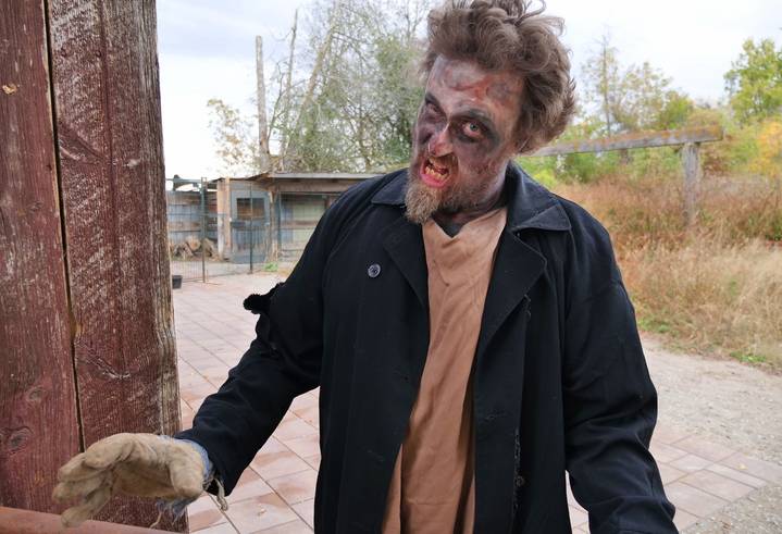 An actor dressed as a zombie menaces the camera