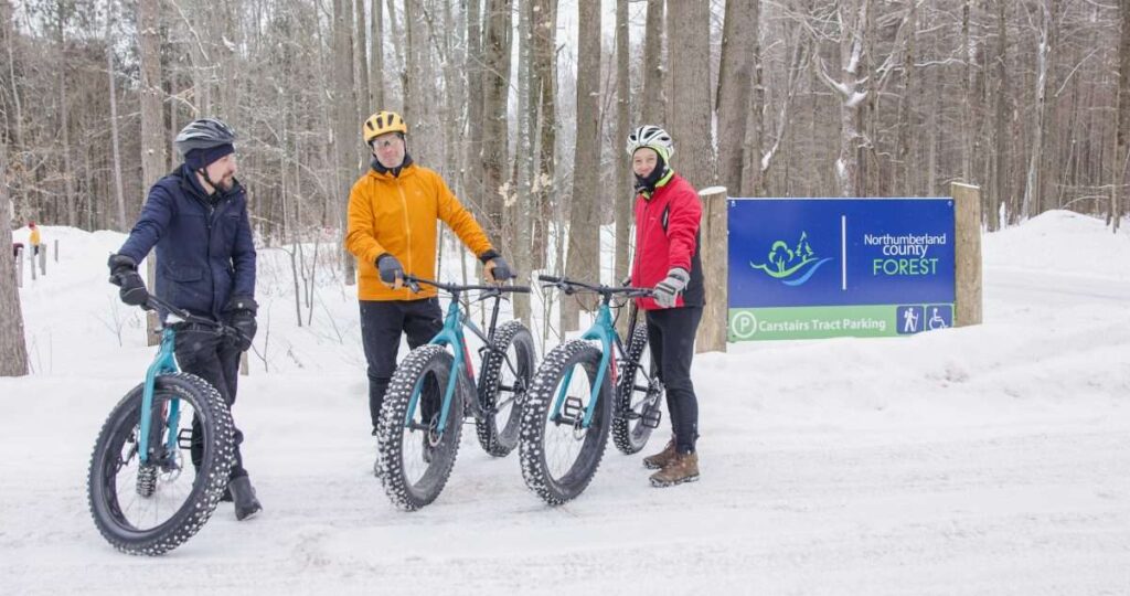 Fat bike riders stand by the Northumberland County Forest sign