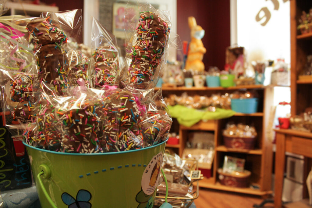 Chocolate with sprinkles in the foreground, candy shop in the background
