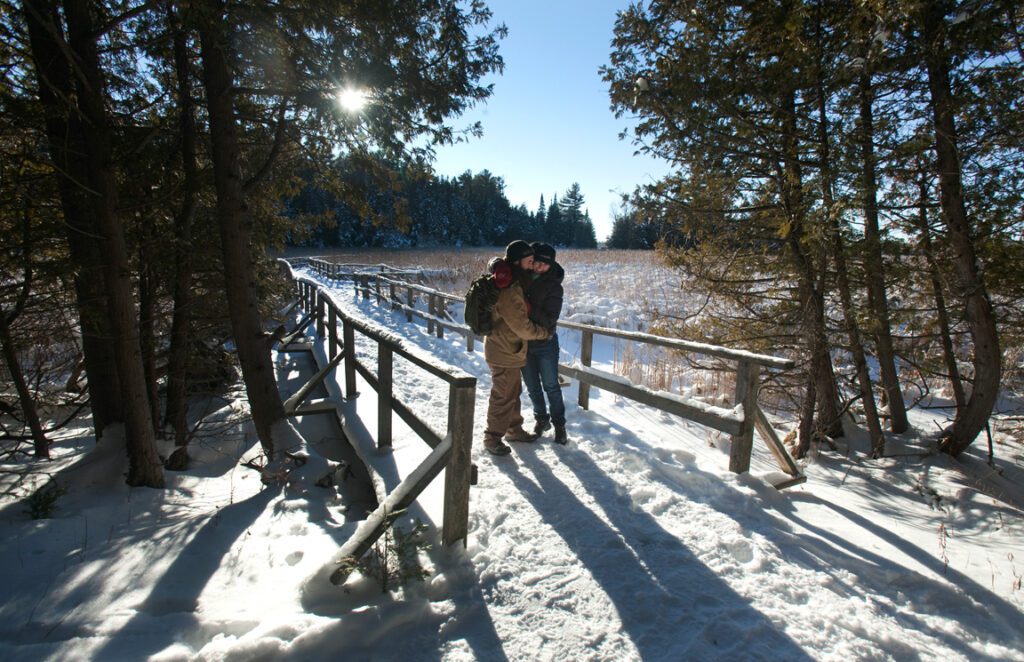 Two people hug on a snowy boardwalk