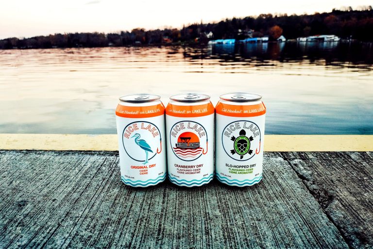 Three cans of Rice Lake hard cider on a dock