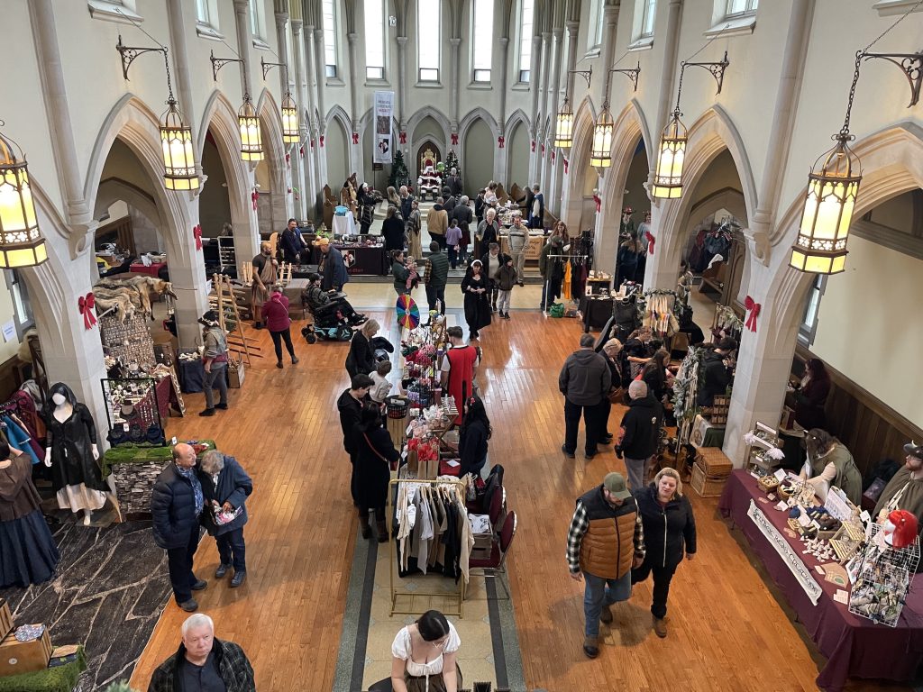 A Christmas market with a medieval theme in a church, seen from a balcony overlooking the floor