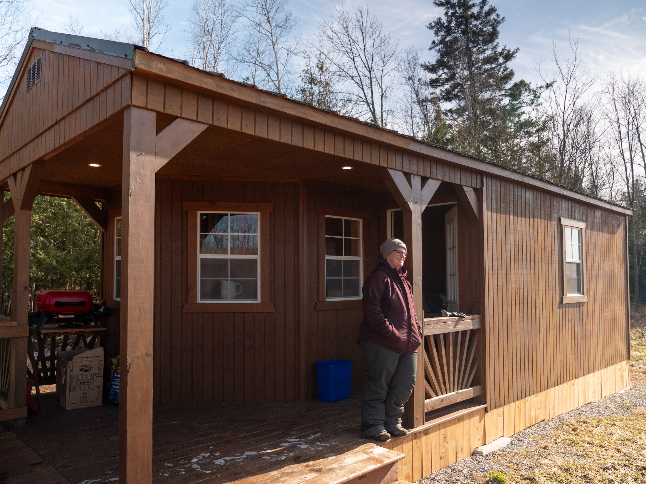 A person leans on a post outside a cabin