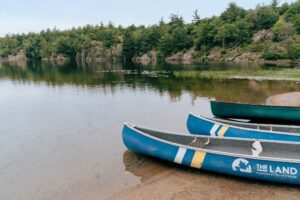 Three canoes lined up on the sandy beach of calm lake