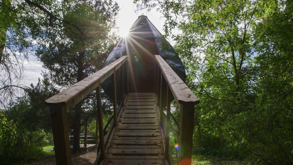 The sun shines behind an Oasis pod  teardrop-shaped camping unit