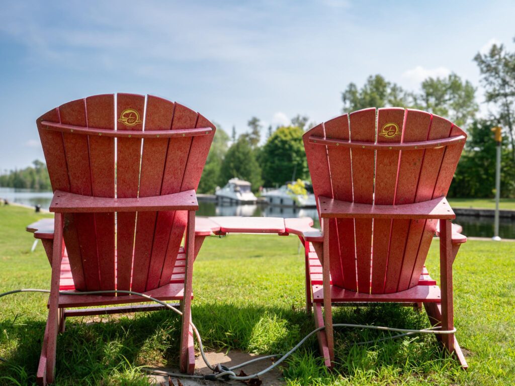 Two red Muskoka chairs, side by side with Parks Canada branding