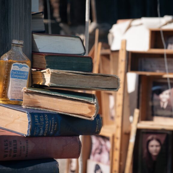 A scultural arrangement of books around a post, accented with old-fashioned items like a bottle of cod-liver oil